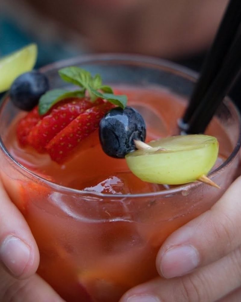 Drink dell'aperitivo del New Circus servito con fragola, mirtilli, uva e menta fresca